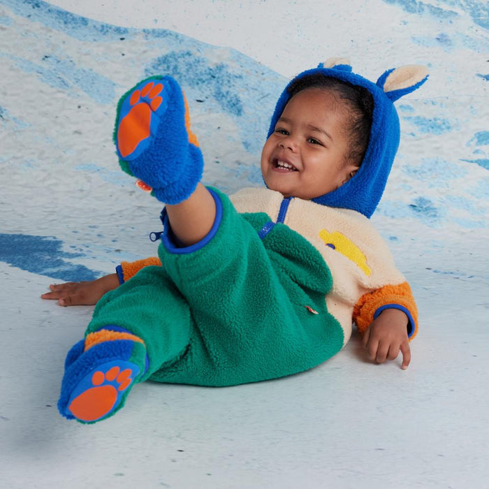 Child wearing a colorful sherpa outfit on a textured blue and white background