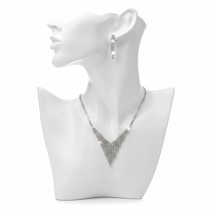 A shimmering silver-toned jewelry set featuring a tapered V-shaped mesh necklace and matching linear drop earrings on a white minimalist bust.