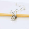 Silver hedgehog charm row counter on a chain with two wooden knitting needles, showing the detailed metallic hedgehog bead