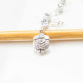 Close-up of silver sheep charm with curly wool texture on numbered bead chain row counter resting on bamboo knitting needle