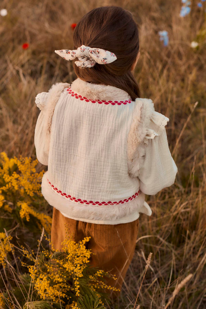 back view of child wearing faux fur lined vest with pink ric rac trim.