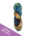 Skein of Yarnaceous Fibers Smuggler's Bay fingering weight sock yarn in deep navy, teal, gold and copper, with a Coming Sept 28th banner