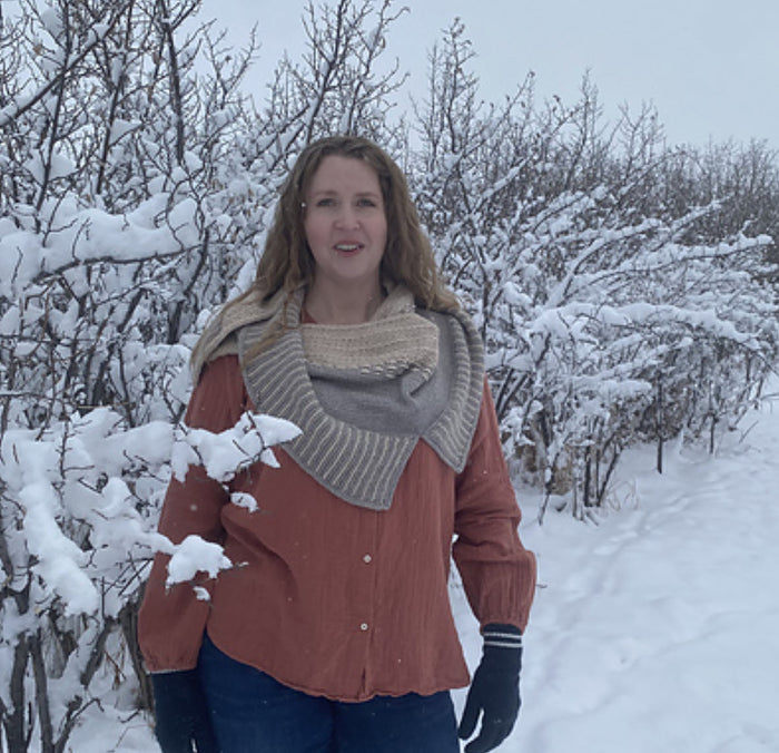 Woman wearing the Snowy Owl shawl as a cowl in gray and cream with a rust blouse in a snowy winter scene