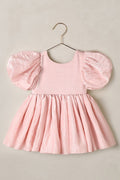 Pink dress with puff sleeves on a hanger against a beige background