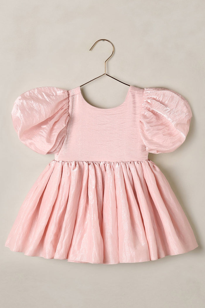 Pink dress with puff sleeves on a hanger against a beige background