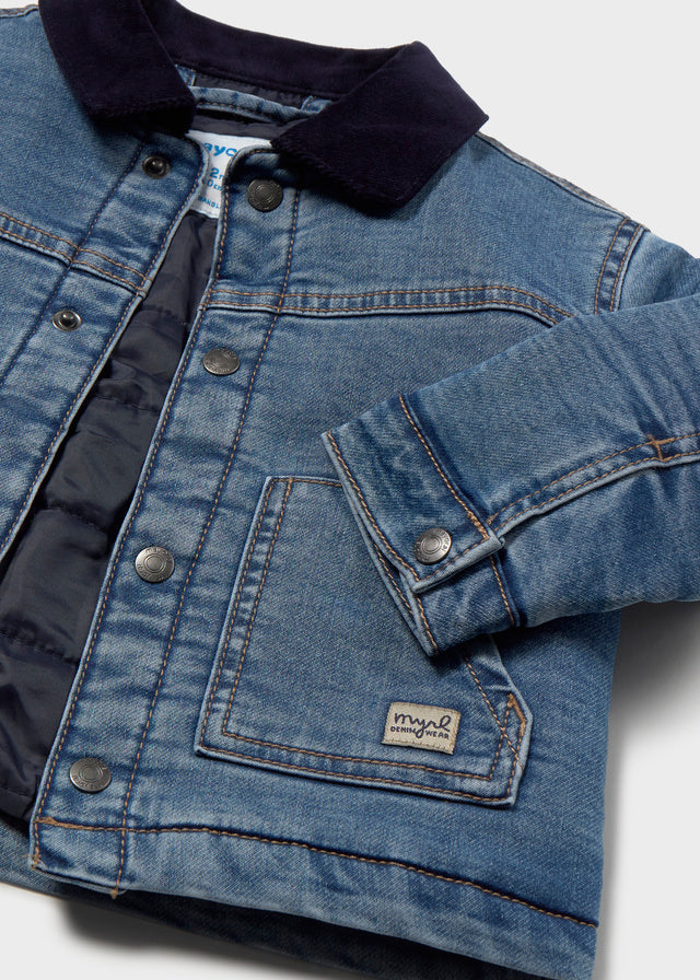 Close-up of a blue denim jacket with a brand label on a light gray background