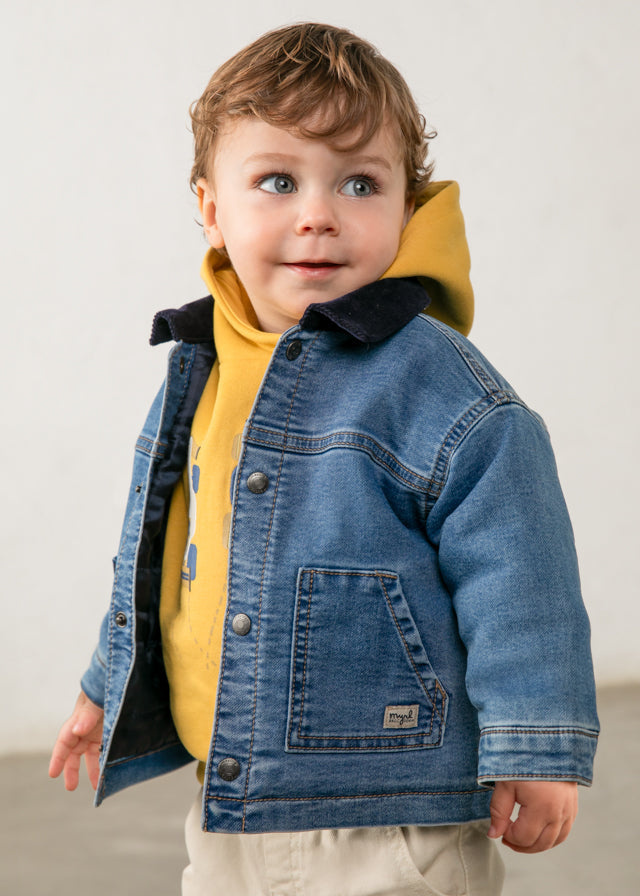 Child wearing a denim jacket over a yellow shirt against a plain background