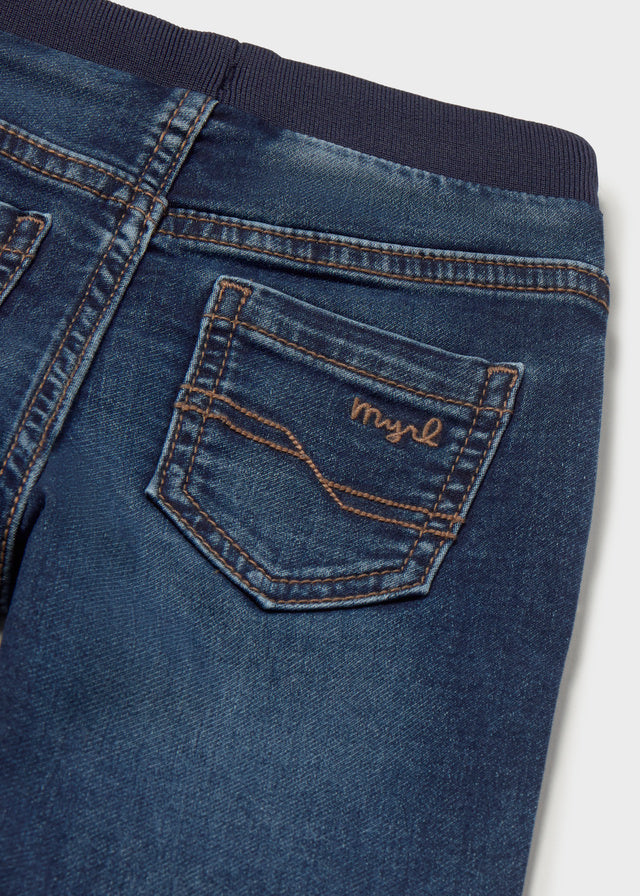 Close-up of blue jeans with a brand logo on the pocket against a white background