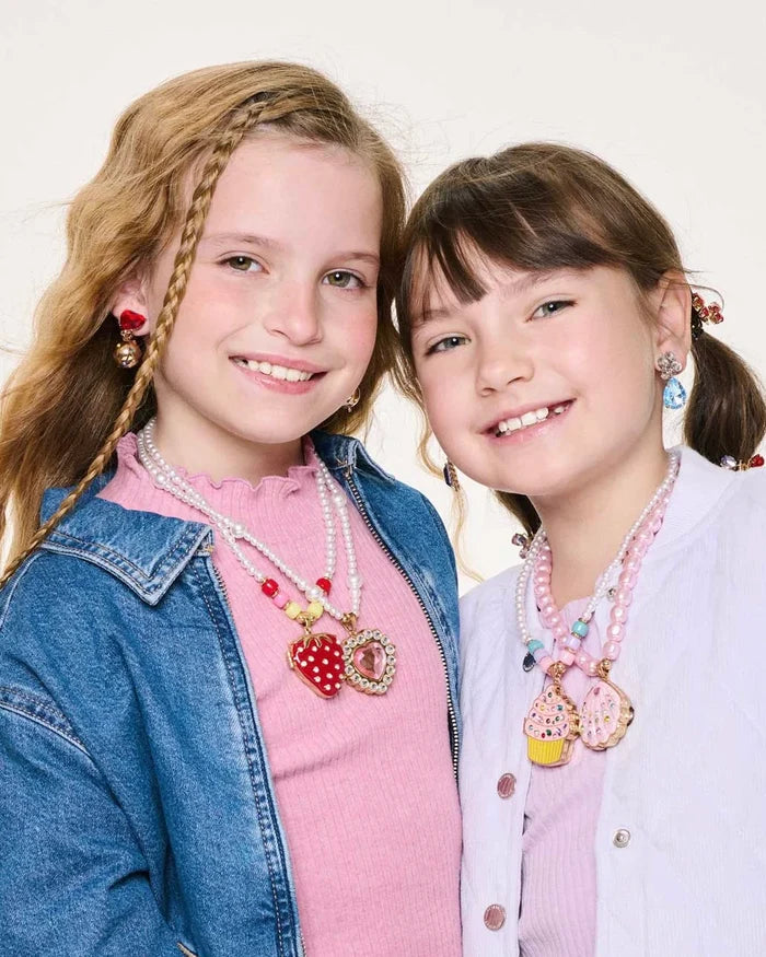 Two young girls wearing colorful necklaces against a white background