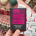 Hand holding the pink and black Spring Doodle Card Deck by Pacific Knit Co tuckbox