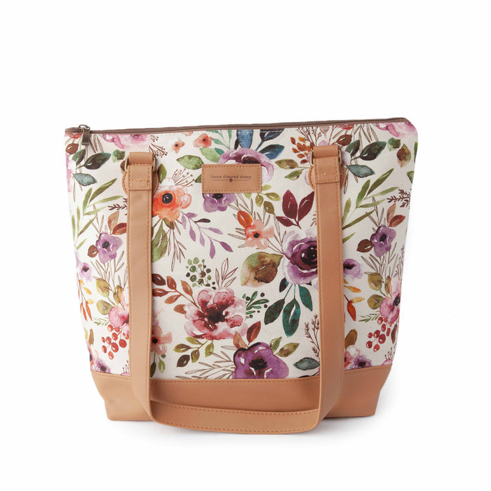 Spring Floral Mega Trinity Bag front view showing large zippered tote with watercolor wildflower print fabric in pink, purple, and green with tan faux leather handles and base
