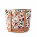 Spring Floral Mega Trinity Bag front view showing large zippered tote with watercolor wildflower print fabric in pink, purple, and green with tan faux leather handles and base