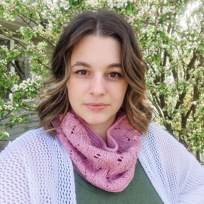 Woman wearing pink lace knit Spring Vibes Cowl with white cardigan outdoors with flowering tree in background
