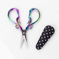 Star Dust Rainbow embroidery scissors with iridescent rainbow flame-shaped handles and star accents shown open with a black and white polka dot leather sheath