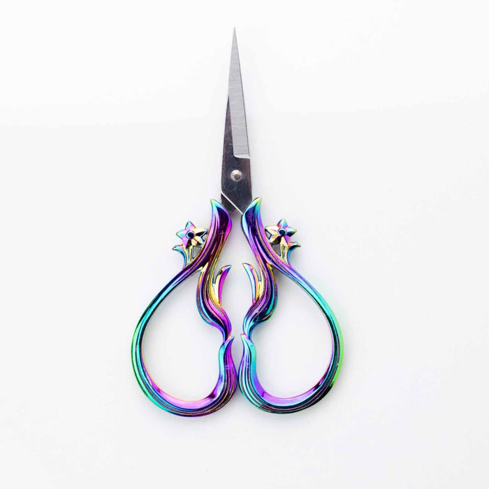 Star Dust Rainbow embroidery scissors shown vertically with blades pointing up displaying the symmetrical iridescent rainbow flame-shaped handles with star accents
