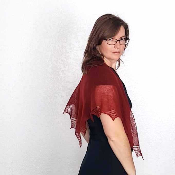 Woman wearing deep red Stardust lace shawl over black dress shown from the side with star point border visible