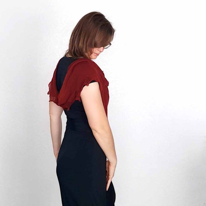 Woman looking down wearing deep red Stardust lace shawl draped over shoulders of black dress