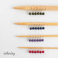 Fairy Lights infinity style stitch markers in green, blue, purple, and red pearl beads on bamboo knitting needles