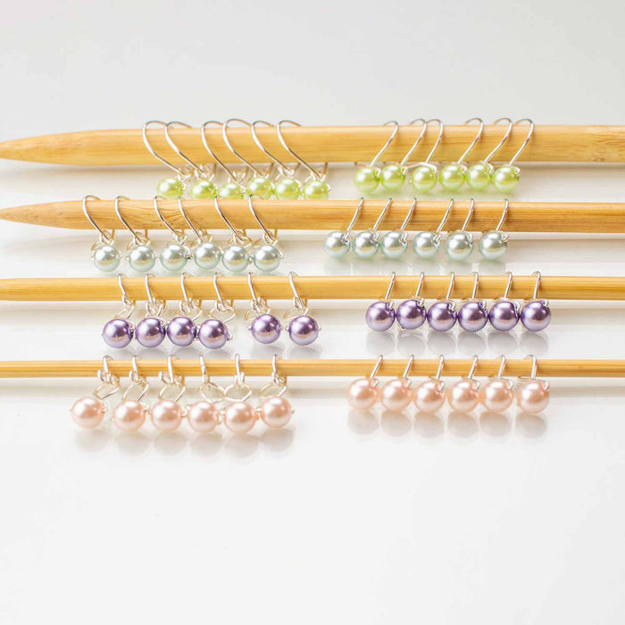 Complete pastel pearls stitch marker starter set showing all 40 markers with 10 per color in green, silver, purple, and pink on bamboo needles