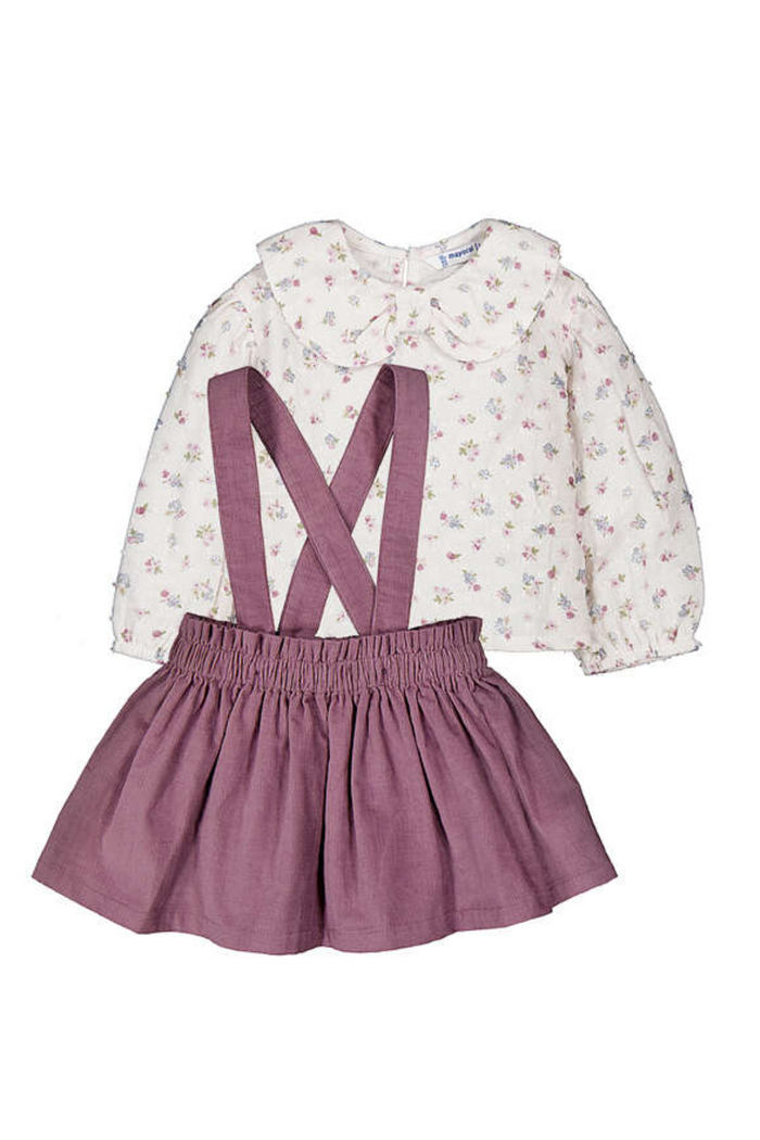 Children's outfit with floral blouse and violet skirt with suspenders on a white background