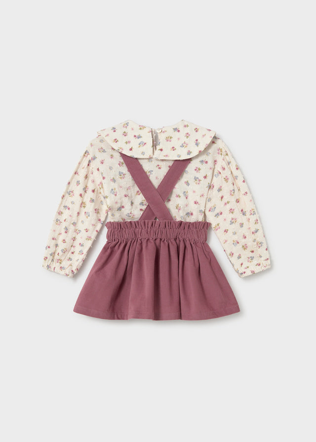 Children's outfit with floral blouse and purple skirt on a light gray background