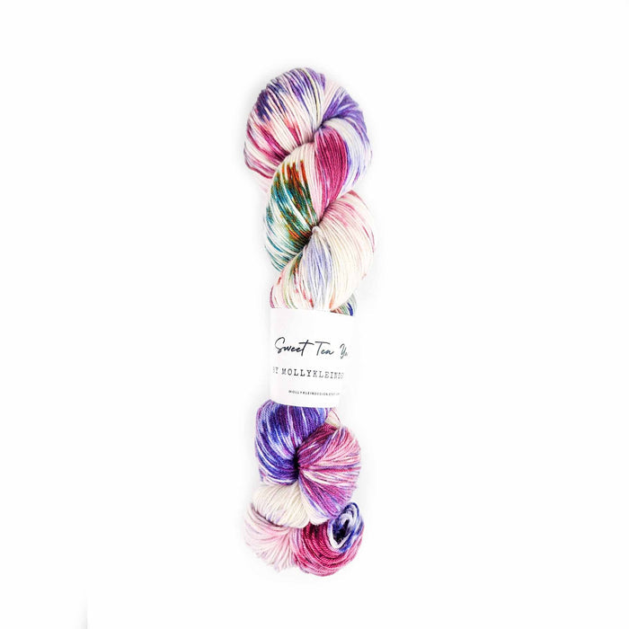 Skein of Sweet Tea Spring Floral fingering weight yarn in pink, purple, teal, and cream variegated dye