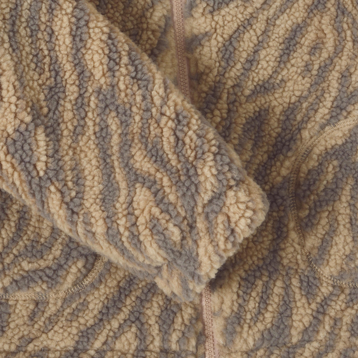 Close-up of a sherpa fleece zip-up jacket with a wavy zebra-like pattern in beige and brown.