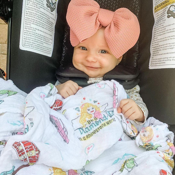 baby in car seat wearing pink oversized bow headband with"Be a Diamond in a Rhinestone World" text printed blanket