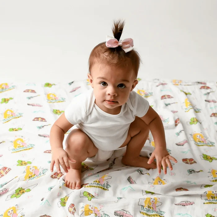 baby squatting on blanket with colorful print allover