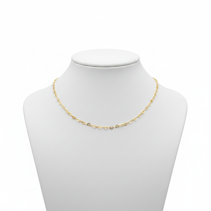 Dainty 18k gold-plated necklace featuring a continuous chain of small interlocking open-heart links, styled on a model wearing a white linen shirt.