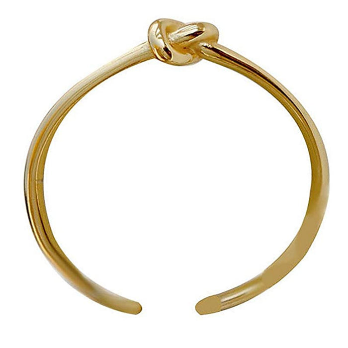 A front-facing studio shot of a polished gold-tone ring featuring a central "love knot" design and an open adjustable band, isolated on a clean white background.