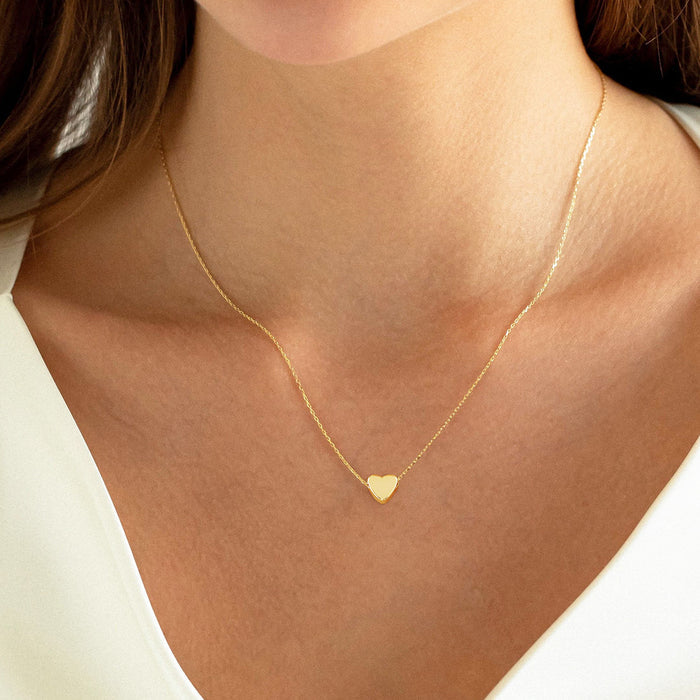 Dainty gold heart pendant necklace on a fine gold chain worn by a woman, minimalist copper jewelry for everyday style.