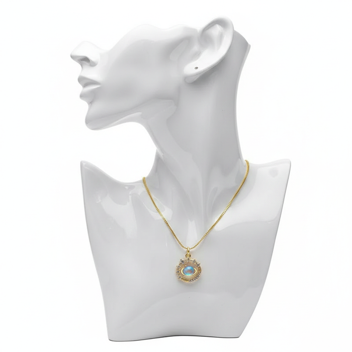 A gold-toned necklace featuring a circular pendant with an iridescent blue opal "evil eye" center. The eye is surrounded by a celestial-inspired halo of clear crystals and small gold beads. The necklace is displayed on a white mannequin bust against a plain white background.