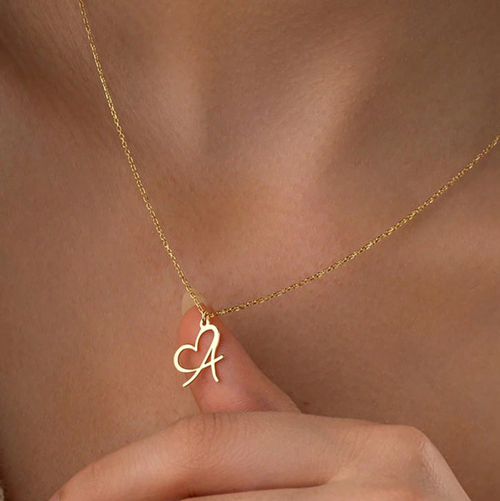 Gold personalized heart initial necklace with a custom script letter pendant, minimalist stainless steel jewelry for women.