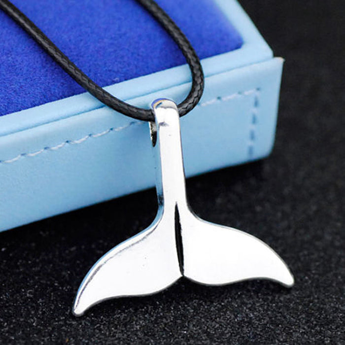 Polished silver shark tail pendant on a black leather rope chain, nautical ocean-inspired necklace for unisex fashion.