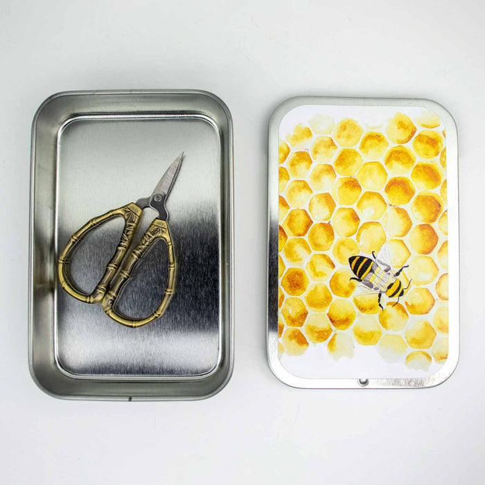 Bronze bamboo thread snips inside open metal tin with watercolor honeybee and honeycomb lid design