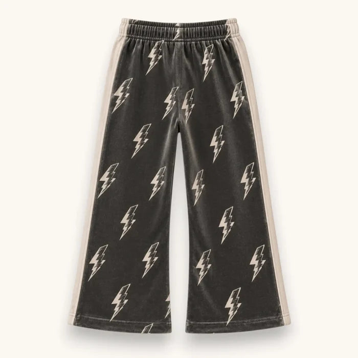 Black wide-leg sweatpants with an all-over white lightning bolt pattern and beige side stripes, shown flat against a light cream background.