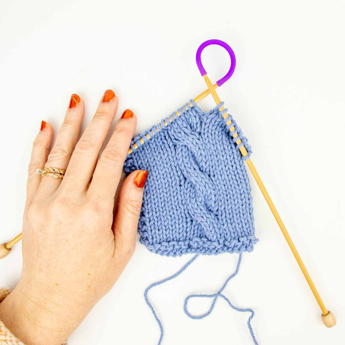 Tip Ties point protectors placed on double pointed needles with blue knitting project keeping stitches secure