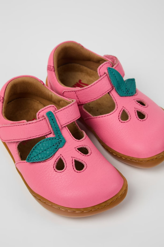 Pink children's shoes with green leaves on a light gray background