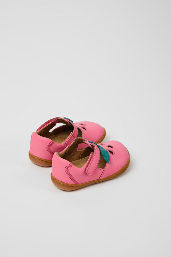 Pair of pink children's shoes with brown soles on a light gray background