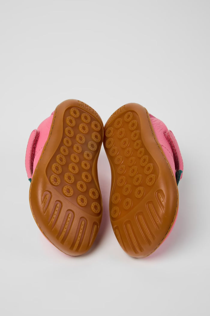 Pink children's shoes with brown soles on a light gray background