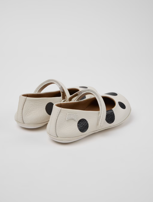 Pair of white shoes with black polka dots on a light gray background