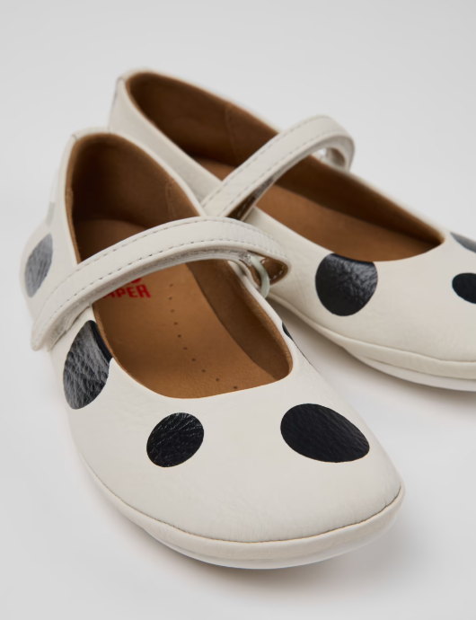 White shoes with black polka dots on a light gray background