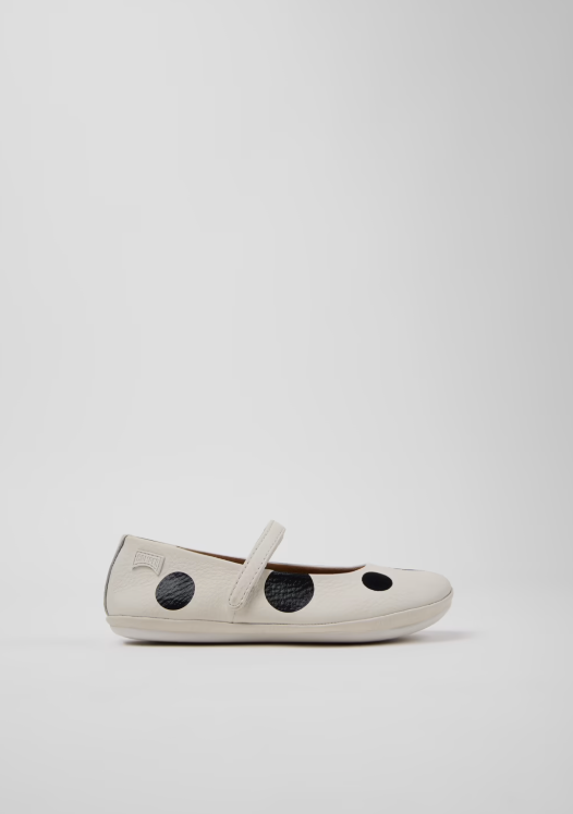 White flat shoe with black polka dots on a light gray background