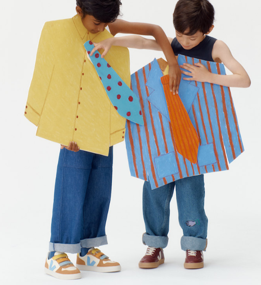 Two children holding up colorful cardigans against a white background