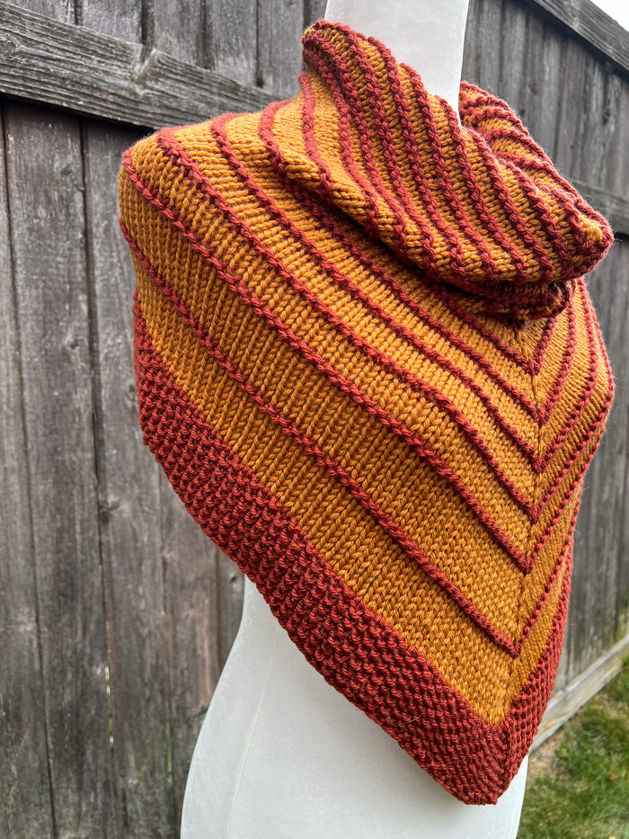 Ochre and Terra Cotta striped knit cowl on white dress form, side view against wood fence
