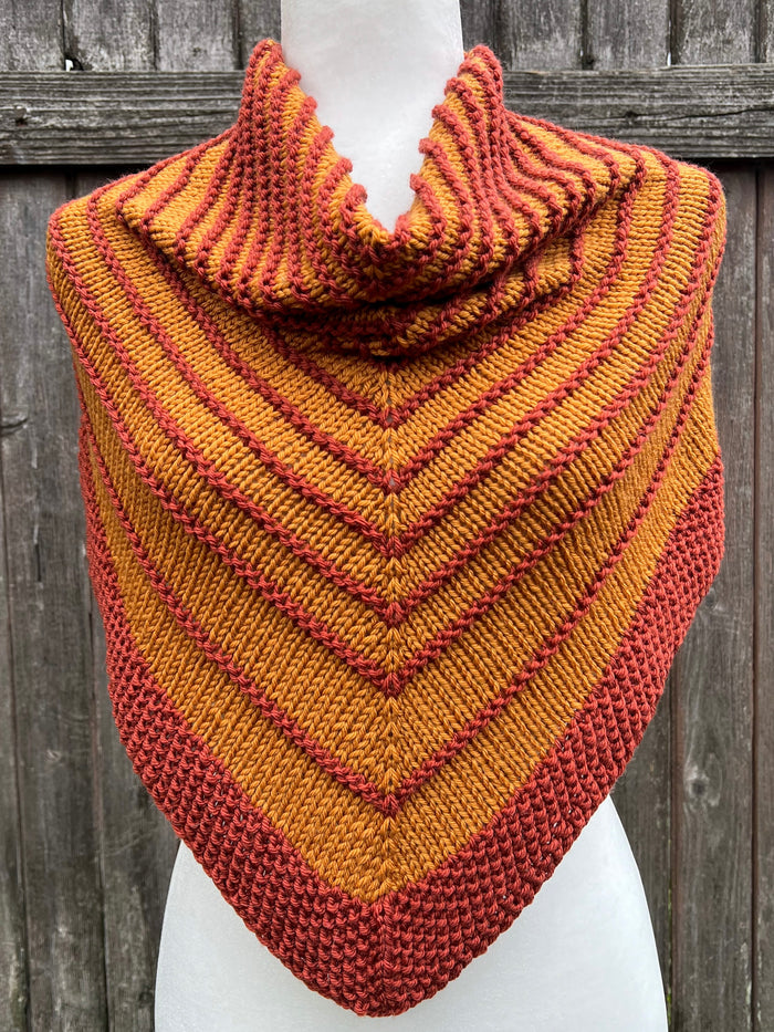 Ochre and Terra Cotta striped knit cowl on white dress form, front view against wood fence
