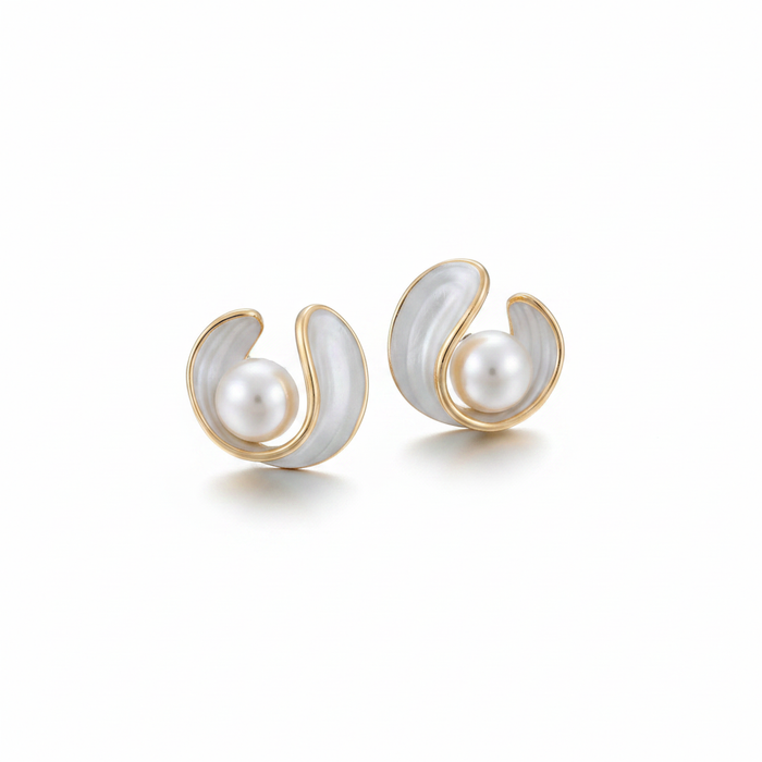 A pair of gold-toned stud earrings featuring a modern, sculptural design. Each earring consists of a curved, wave-like gold frame filled with white enamel or mother-of-pearl inlay, cradling a single round white pearl in the center. The jewelry is shown against a clean white background with soft shadows.