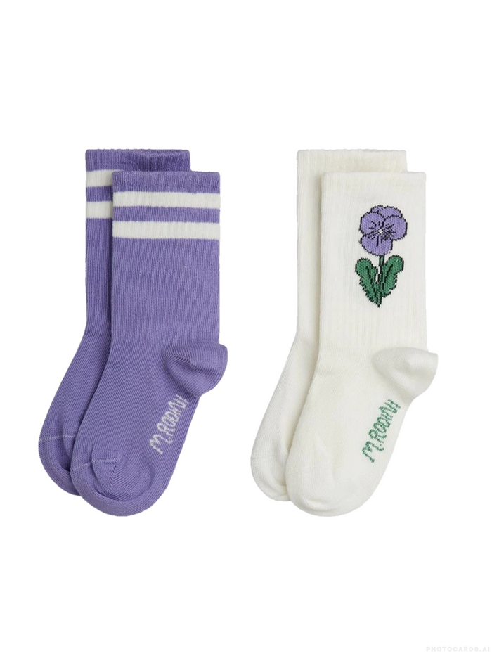 Two pairs of socks on a plain white background: one pair is lavender purple with two white stripes, and the other pair is off-white with a purple flower and green leaf graphic on the front.