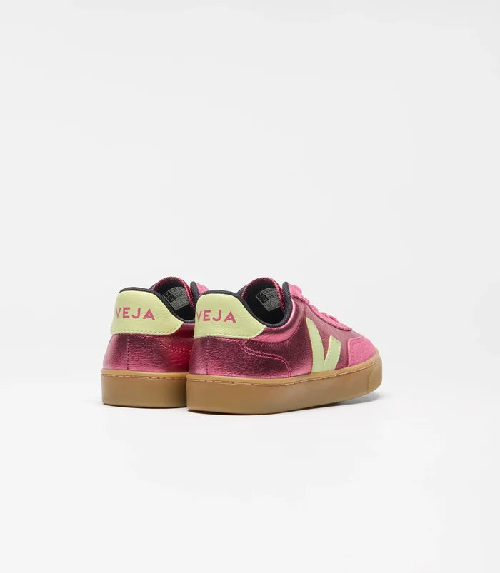 A pair of vintage-style low-top sneakers shown from the back, featuring a metallic magenta-pink leather upper, a pale yellow heel tab with 'VEJA' printed in pink, and a tan gum sole, set against a plain light gray background.